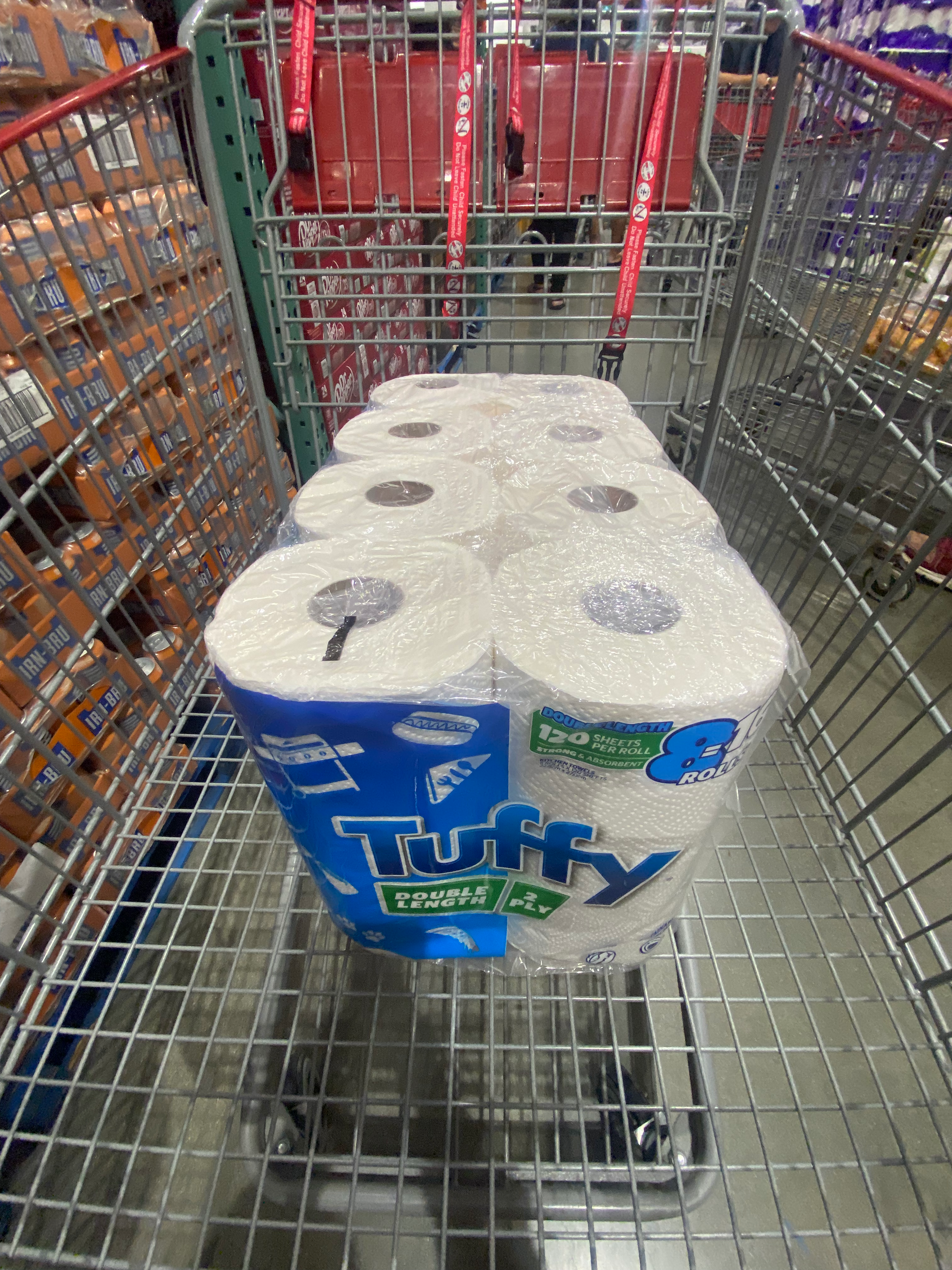 8 pack of paper towels wrapped in a plastic covering with brand name Tuffy Paper Towel side angle on a shopping cart for sale for costco online shopping. 